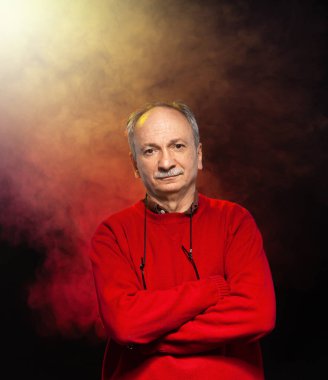 Gözlüklü, kırmızı kazaklı yaşlı bir adamın stüdyo portresi.