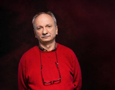 Gözlüklü, kırmızı kazaklı yaşlı bir adamın stüdyo portresi.
