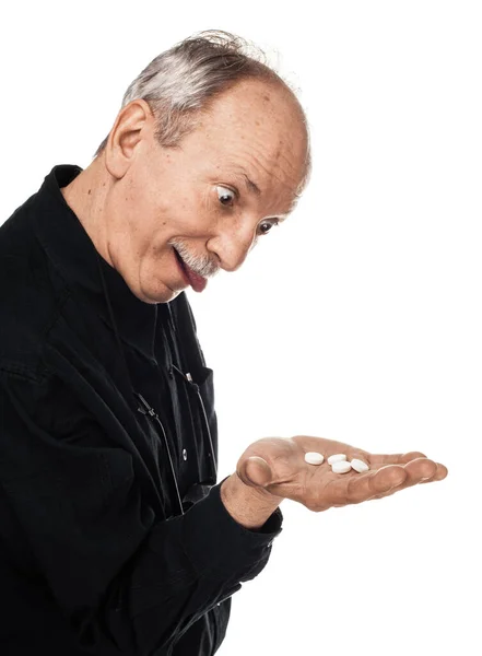 医学と健康の概念 目を腫らせ白い背景に錠剤を手に舌を突き出す高齢者 老人は薬を飲みたがってる — ストック写真