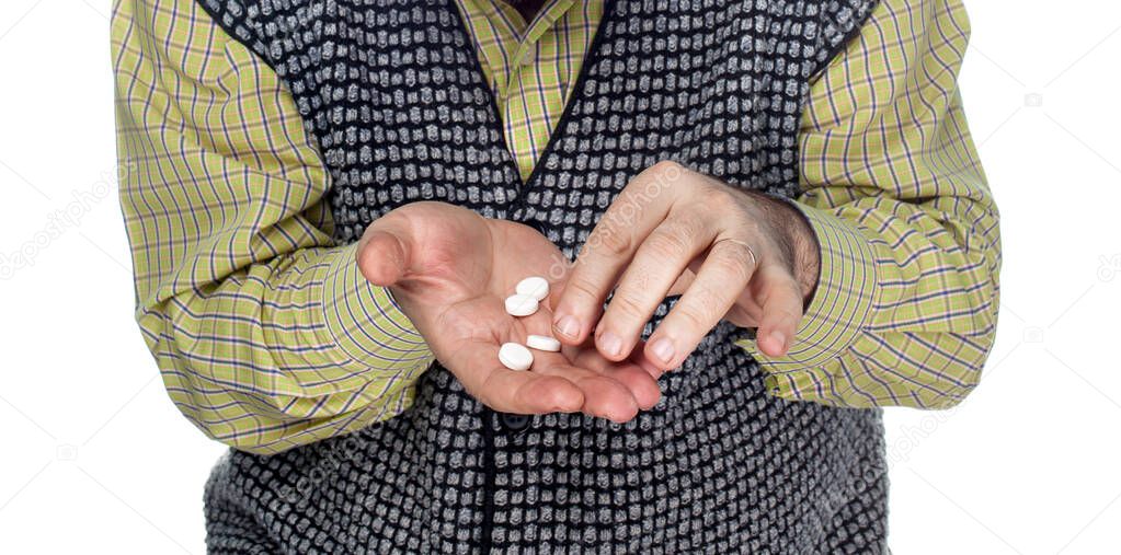 Medicine and health concept. Hands of an elderly man with pills on a white background. Old man wants to take a pill