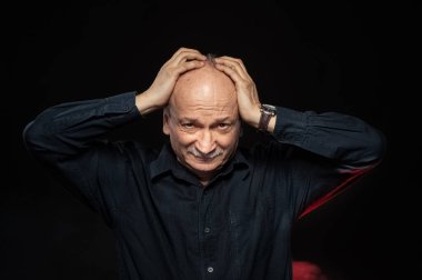 Yaşlı maço adam. Stüdyonun karanlık arka planında yaşlı duygusal bir adamın portresi.