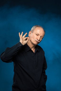 Yaşlı maço adam. Stüdyonun karanlık arka planında yaşlı duygusal bir adamın portresi.