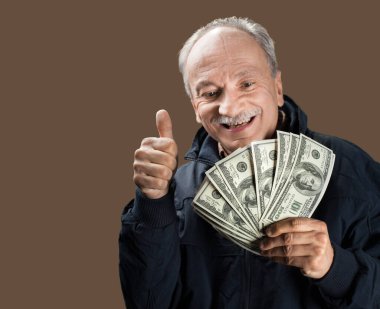 Kıdemli beyefendi bir tomar para tutuyor. Heyecanlı yaşlı bir adamın portresi. Dolarlık banknotlar tutan mutlu yaşlı adam..