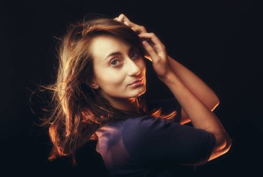 Karanlık arka planda genç bir kadının romantik bir portresi.