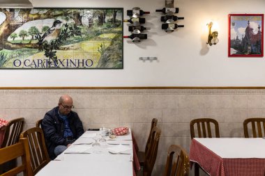 LISBON, PORTUGAL - 18 Aralık 2017: Lizbon, Portekiz 'deki caddedeki kafe. Yaşlı bir adam emirlerini bekliyor.