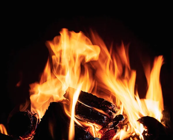 在壁炉里生火深色背景下的火焰和烧焦的柴火 — 图库照片