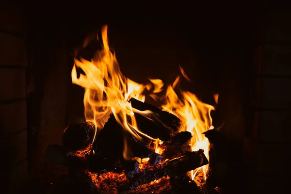 在壁炉里生火深色背景下的火焰和烧焦的柴火 — 图库照片