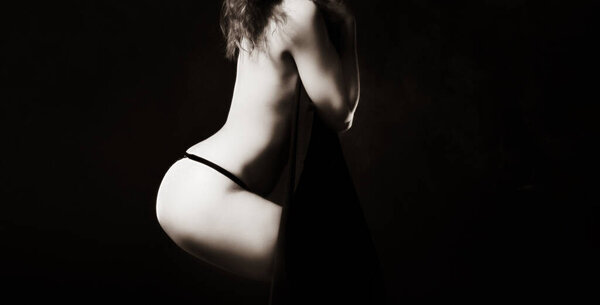 Elegant woman and beauty concept. Half-naked woman posing in the studio. View from the back