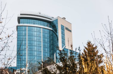 Kyiv, Ukrayna - Nisan. 18, 2018: Hilton Kyiv parktaki ağaçların arkasındaki cam bina