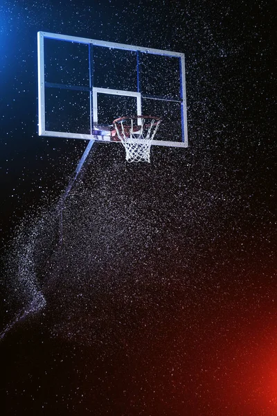 Arco de basquete isolado em preto. Arena de basquete sob chuva. Iluminado por luzes coloridas misturadas . — Fotografia de Stock