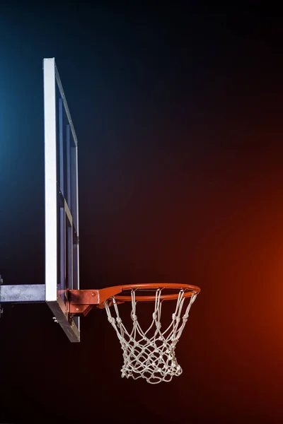 Arco de basquete isolado em preto. Iluminado por luzes coloridas misturadas . — Fotografia de Stock