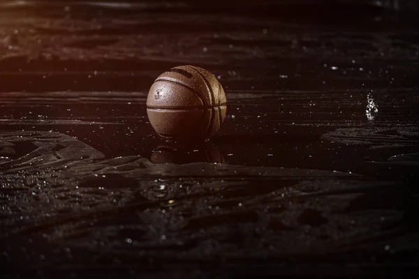 Basketball auf nassem Court-Boden aus nächster Nähe mit verschwommenem Hintergrund. unter dem Regen. — Stockfoto