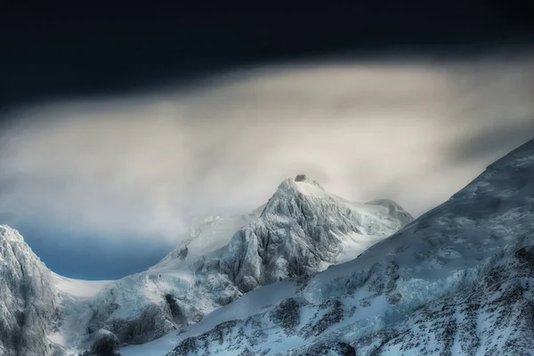 Toppen af Høje Bjerge, dækket af sne. Vinterbjerge på en lys solrig dag. Alper bjerglandskab med overskyet himmel . - Stock-foto