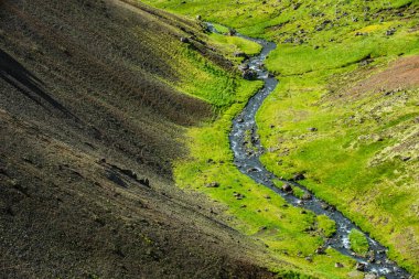 Muhteşem İzlanda doğa manzarası. Yukarıdan bak. Yüksek dağlar, dağ nehri ve yeşil çayırlar. Yeşil çayırlar. İzlanda.