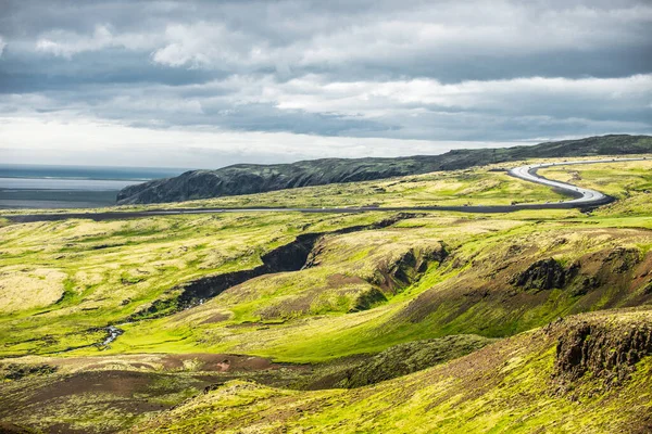 Wunderbare isländische Naturlandschaft. Blick von oben. Hohe Berge, Teerstraße, Gebirgsfluss und grüne Wiesen. — Stockfoto