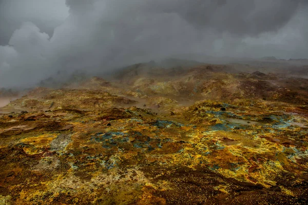 A paisagem colorida na área geotérmica. Ventilação de vapor sulfúrico quente vomitando vapor de enxofre na área geotérmica quente Islândia. Cor e mineral rico chão enlameado texturizado na frente . — Fotografia de Stock