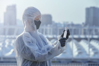 Coronavirus Covid 19, bilim adamının elindeki örnek tüpte enfekte olmuş. Şehrin önündeki koruyucu giysi doktoru..