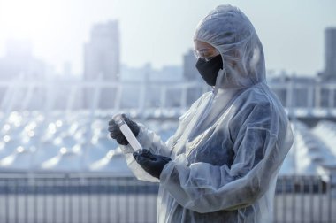 Coronavirus Covid 19, bilim adamının elindeki örnek tüpte enfekte olmuş. Şehrin önündeki koruyucu giysi doktoru..