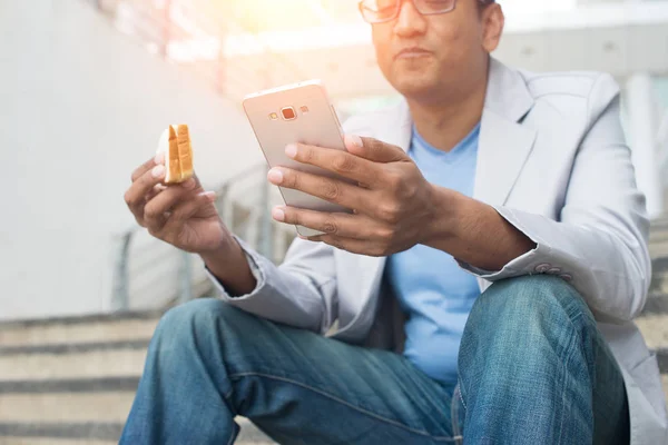 Biznesmen jedzenie kanapka przy użyciu mobilnych — Zdjęcie stockowe