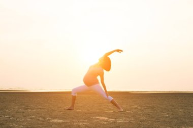 Hamile anne kumsalda Yoga gerçekleştirme