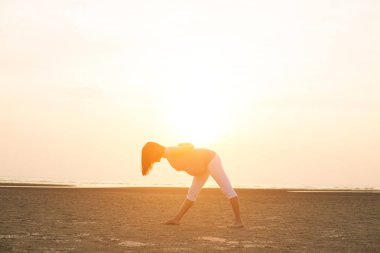 Hamile anne kumsalda Yoga gerçekleştirme