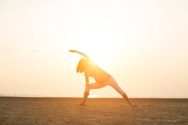 Hamile anne kumsalda Yoga gerçekleştirme