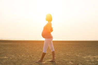 Hamile anne kumsalda Yoga gerçekleştirme