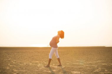 Hamile anne kumsalda Yoga gerçekleştirme