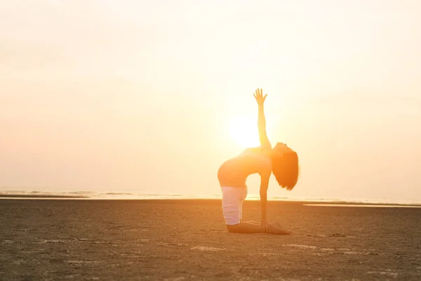 Hamile anne kumsalda Yoga gerçekleştirme — Stok fotoğraf