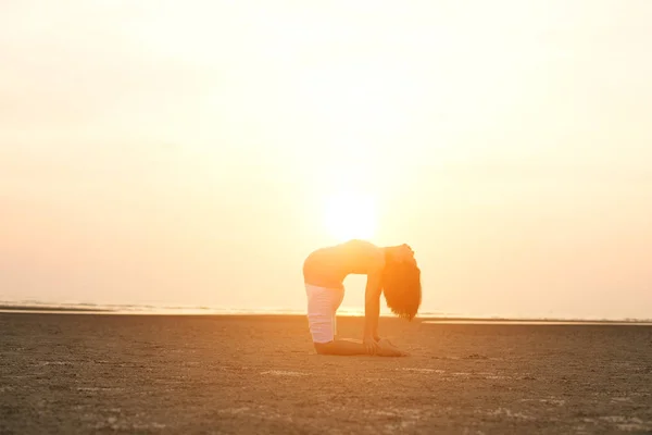 Mère enceinte effectuant du yoga sur la plage — Photo