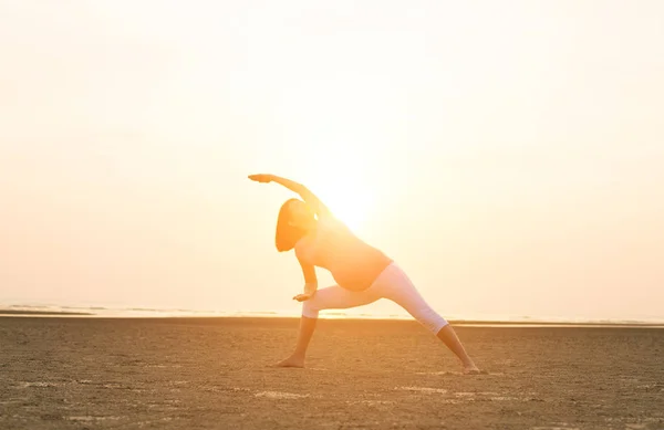 Hamile anne kumsalda Yoga gerçekleştirme — Stok fotoğraf