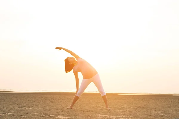 Hamile anne kumsalda Yoga gerçekleştirme — Stok fotoğraf