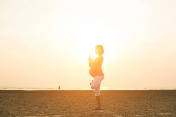 Várandós anya teljesítő jóga beach — Stock Fotó