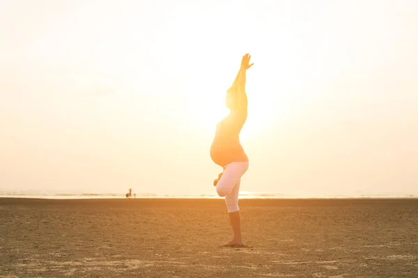 Madre embarazada realizando yoga en la playa —  Fotos de Stock