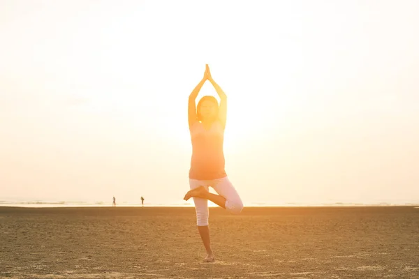 Hamile anne kumsalda Yoga gerçekleştirme — Stok fotoğraf