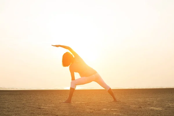 Zwangere moeder uitvoeren van yoga op het strand — Stockfoto