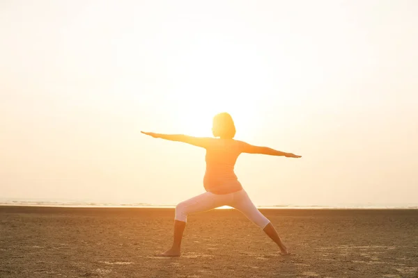 Hamile anne kumsalda Yoga gerçekleştirme — Stok fotoğraf