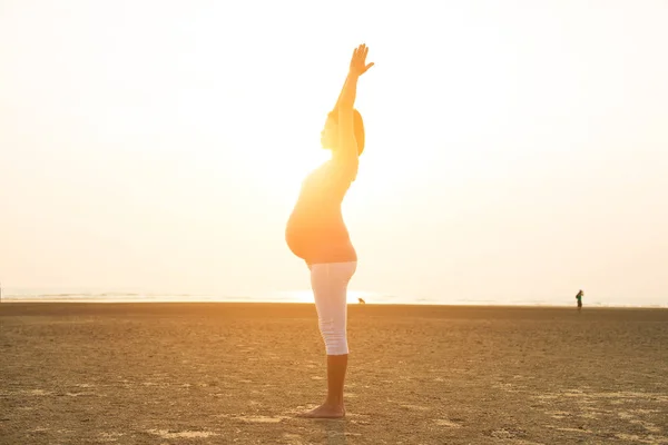 Madre incinta che esegue yoga sulla spiaggia — Foto Stock