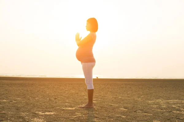 Matki w ciąży, wykonując jogi na plaży — Zdjęcie stockowe