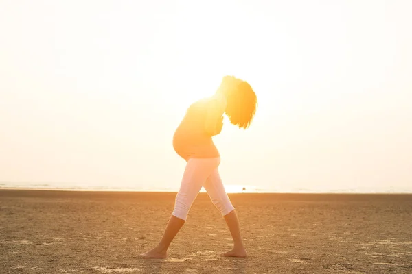 Gravid mamma utför yoga på stranden — Stockfoto