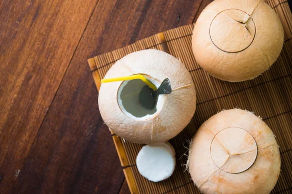 Cocos con paja sobre mesa de madera — Foto de Stock