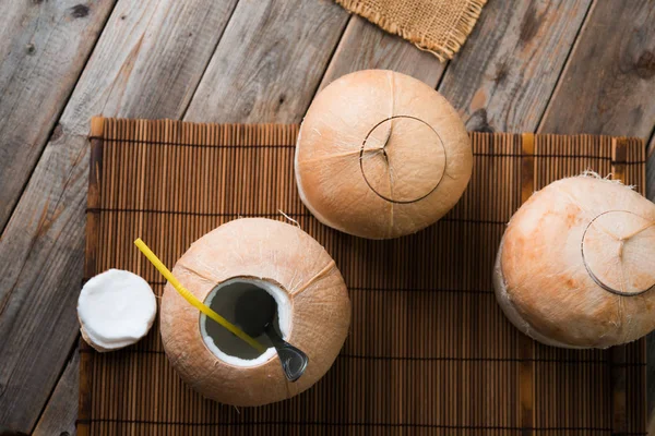 Kokosnötter med sugrör på träbord — Stockfoto