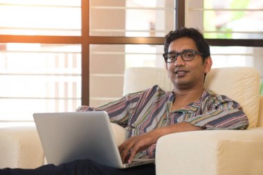 Kanepenin üzerinde bilgisayar kullanan adam