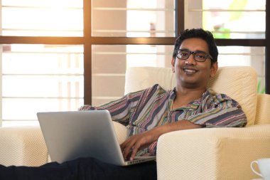 Kanepenin üzerinde bilgisayar kullanan adam