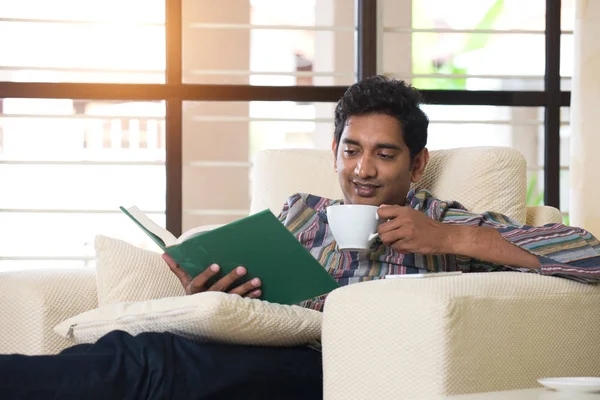 Человек читает книгу на диване — стоковое фото