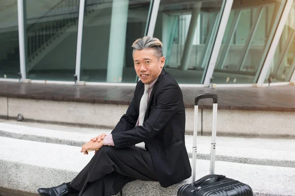 Muž sedící s kufrem — Stock fotografie