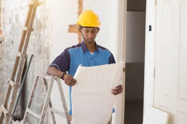 İnşaat işçisi planlara bakıyor.