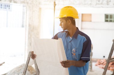 İnşaat işçisi planlara bakıyor.