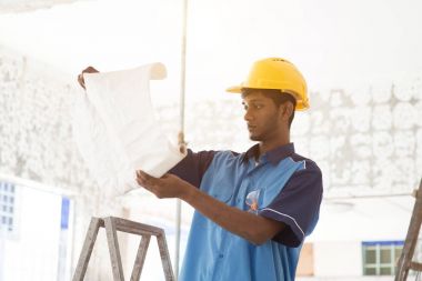 İnşaat işçisi planlara bakıyor.