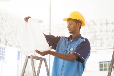İnşaat işçisi planlara bakıyor.